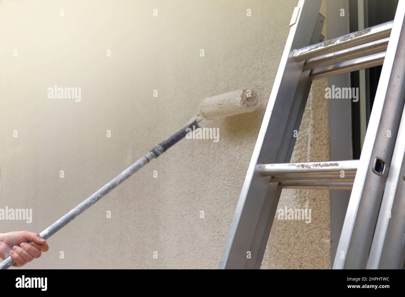 wall painting.Construction roller and metal building ladder on a beige