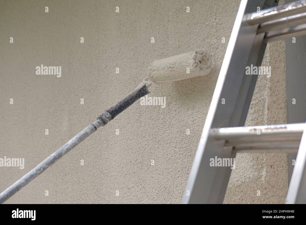 roller and metal building ladder on a beige wall.Home renovation