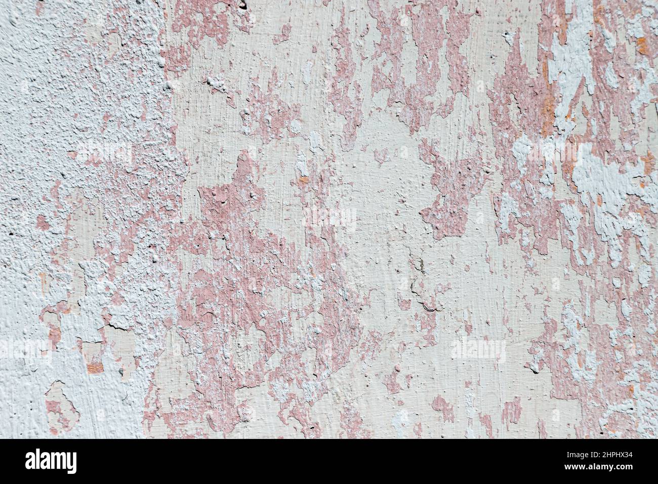 Cracked, plastered concrete wall, with remnants of whitewash and pink