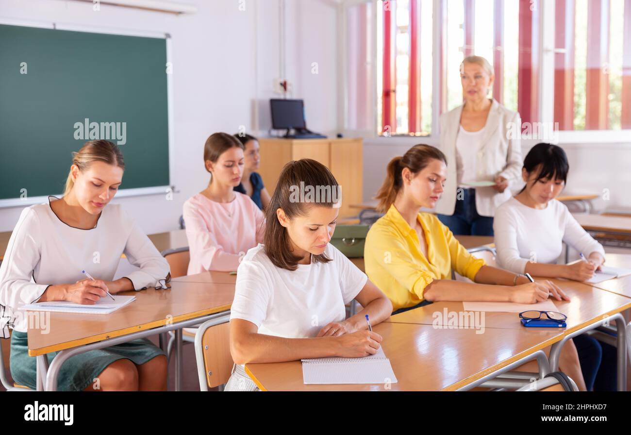 Students writing in notepads during lesson Stock Photo