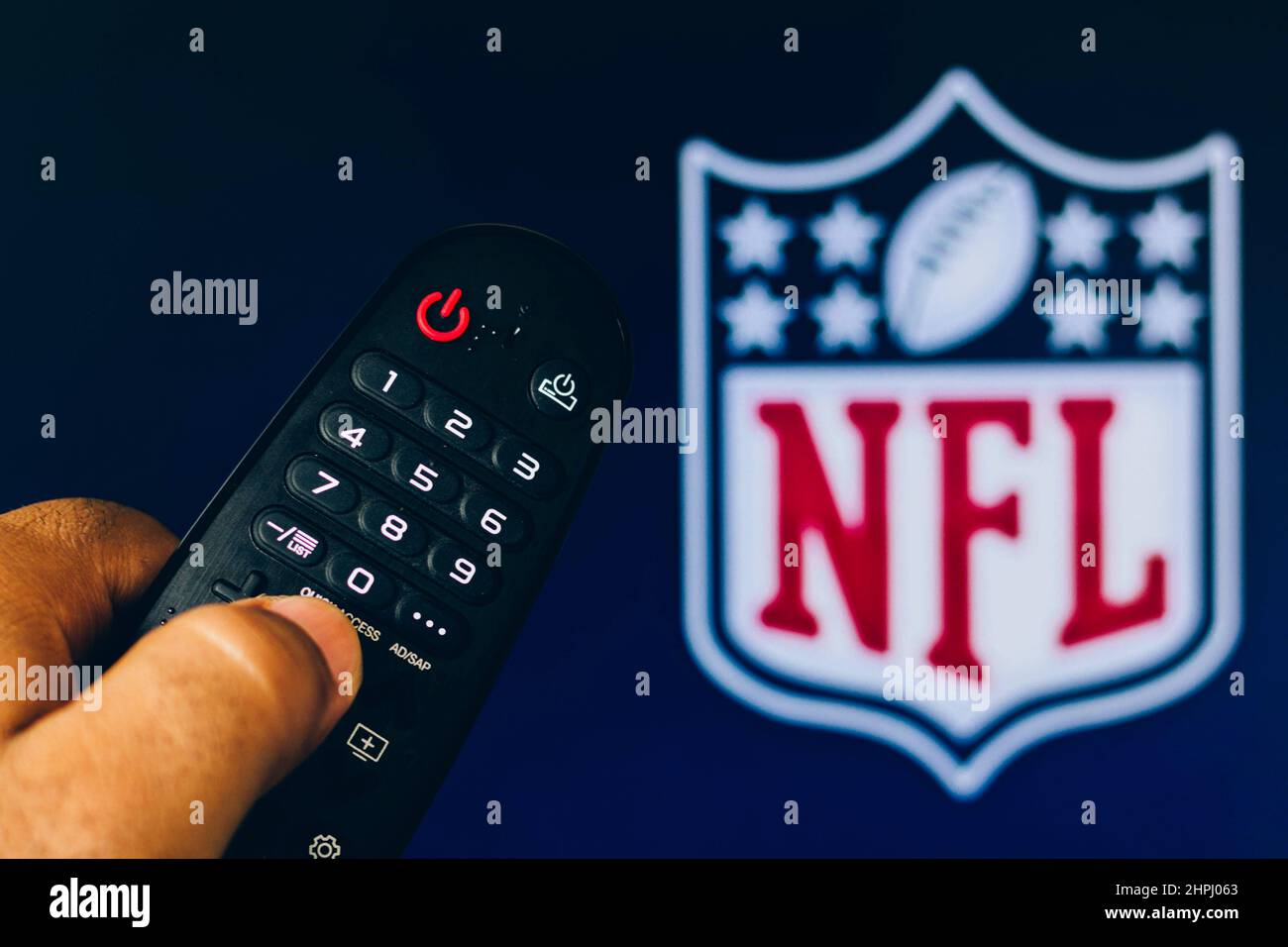 In this photo illustration a close-up of a hand holding a TV remote control seen displayed in front of the NFL Network logo