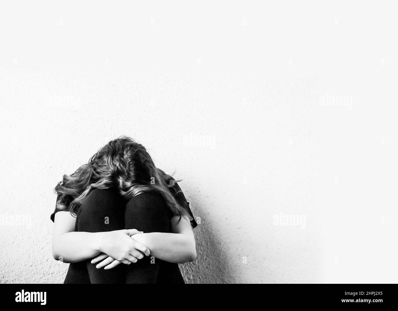 Depressed and lonely girl on the floor feeling miserable and anxious cry with a light background Stock Photo