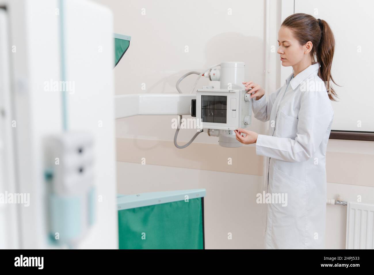 Hospital Radiology Room. Xray machine for fluorography. Doctor radiologist in gown adjusting the