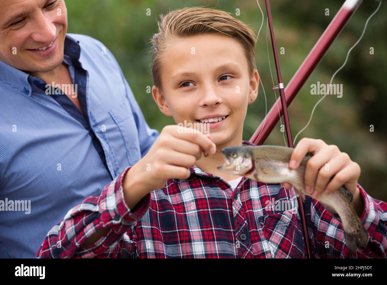 Happy man with son looking at fish on hook Stock Photo