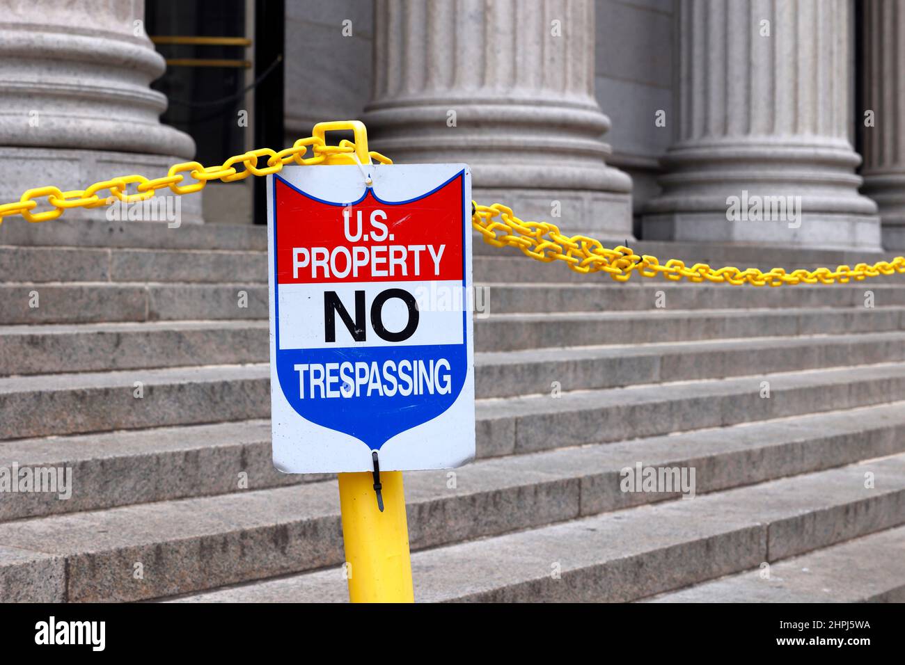 A sign reads 'US Property No Trespassing' on the steps of a building. Stock Photo