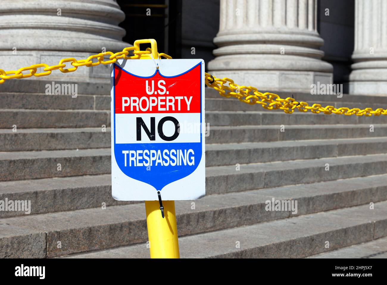 A sign reads 'US Property No Trespassing' on the steps of a building. Stock Photo