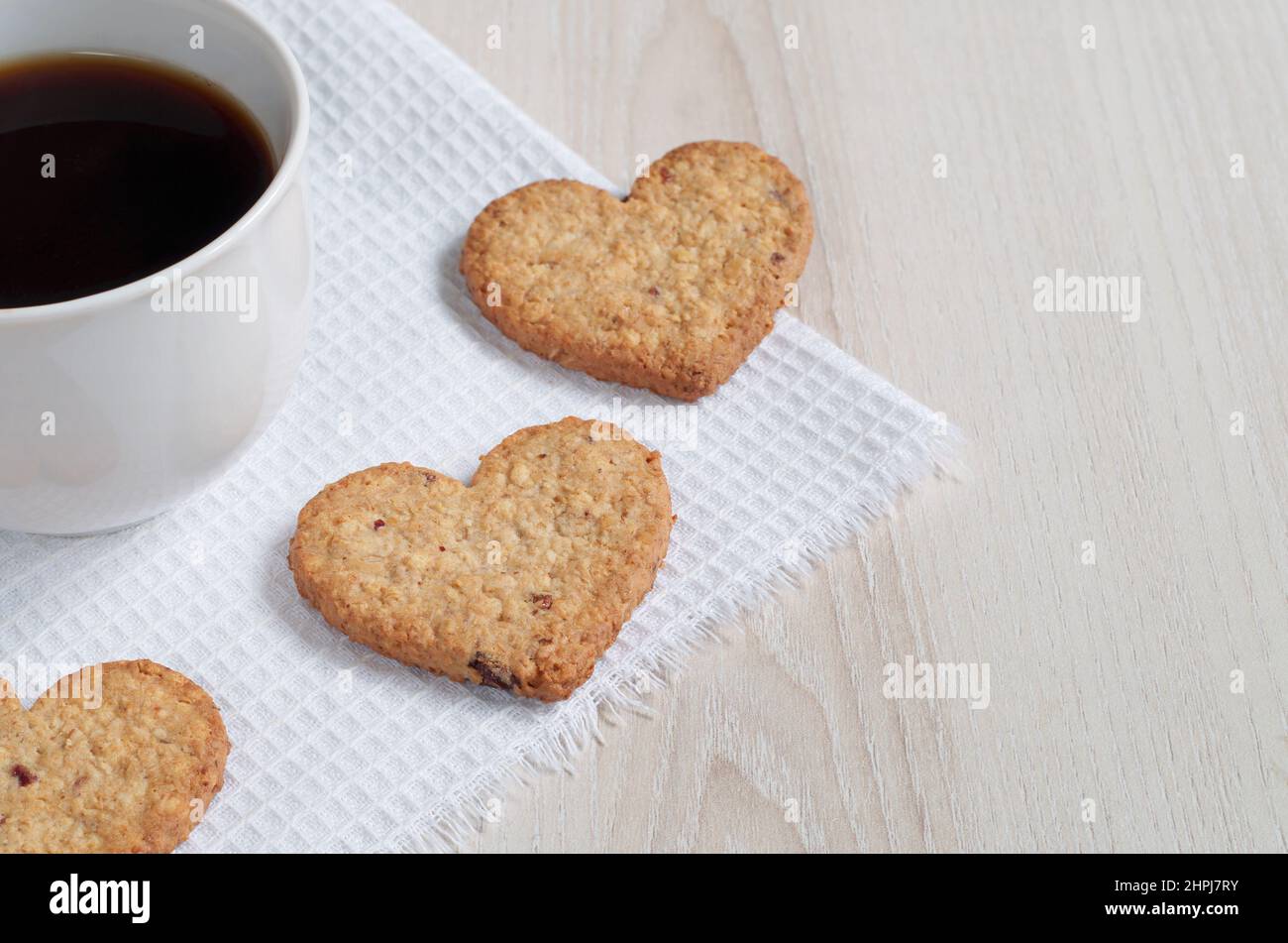 Heartshaped oatmeal cookies and a cup of coffee on a white kitchen