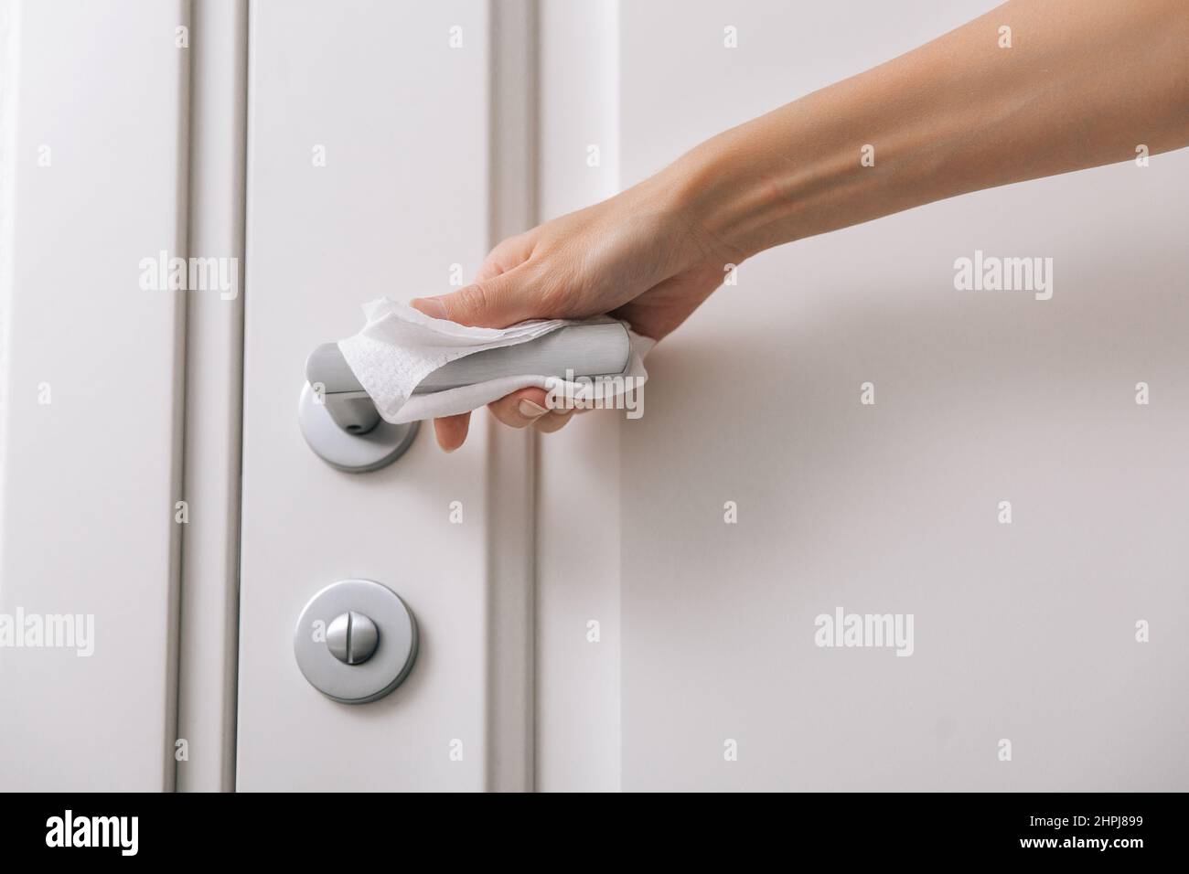 Cleaning door handles with an antiseptic wet wipe and gloves. Woman
