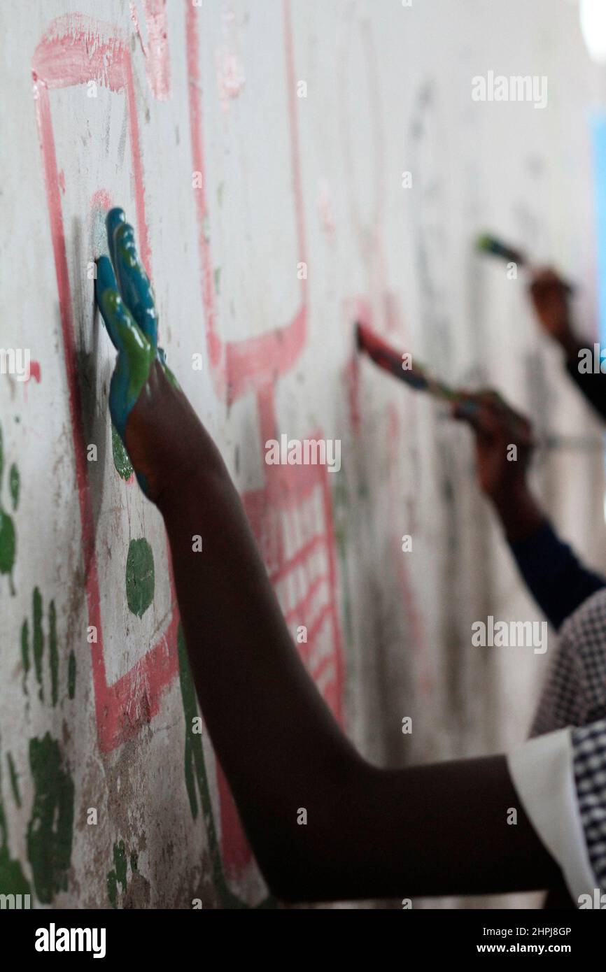 Schoolchildren paint the walls of their school hall at Macheke Primary School. The children were given free reign to draw anything they wanted. Zimbabwe. Stock Photo