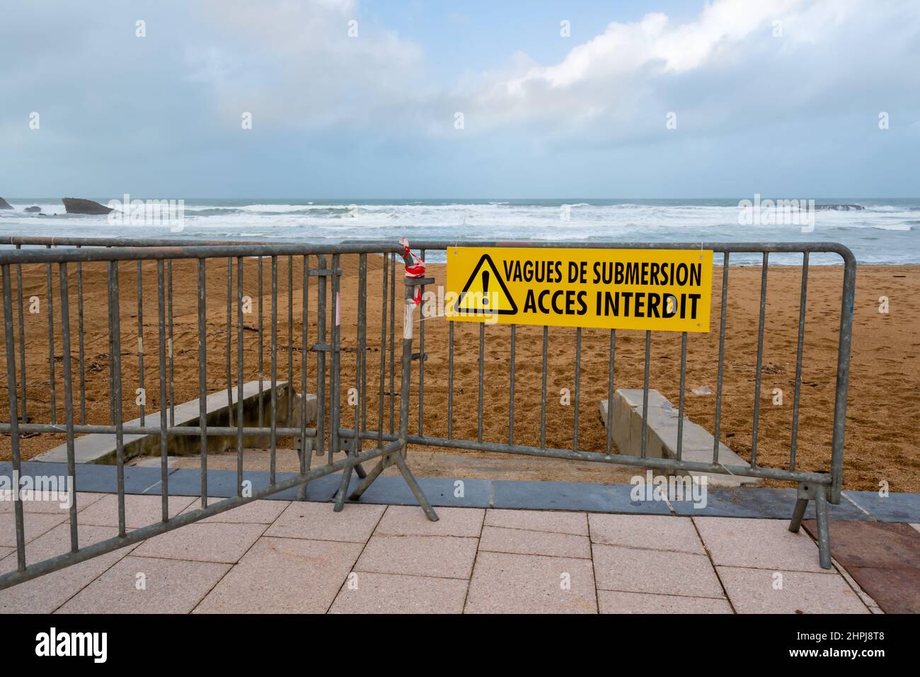 Warning sign on a metal barrier prohibiting access to the beaches of the Atlantic coast reading "Flood waves - Access prohibited" written in French Stock Photo