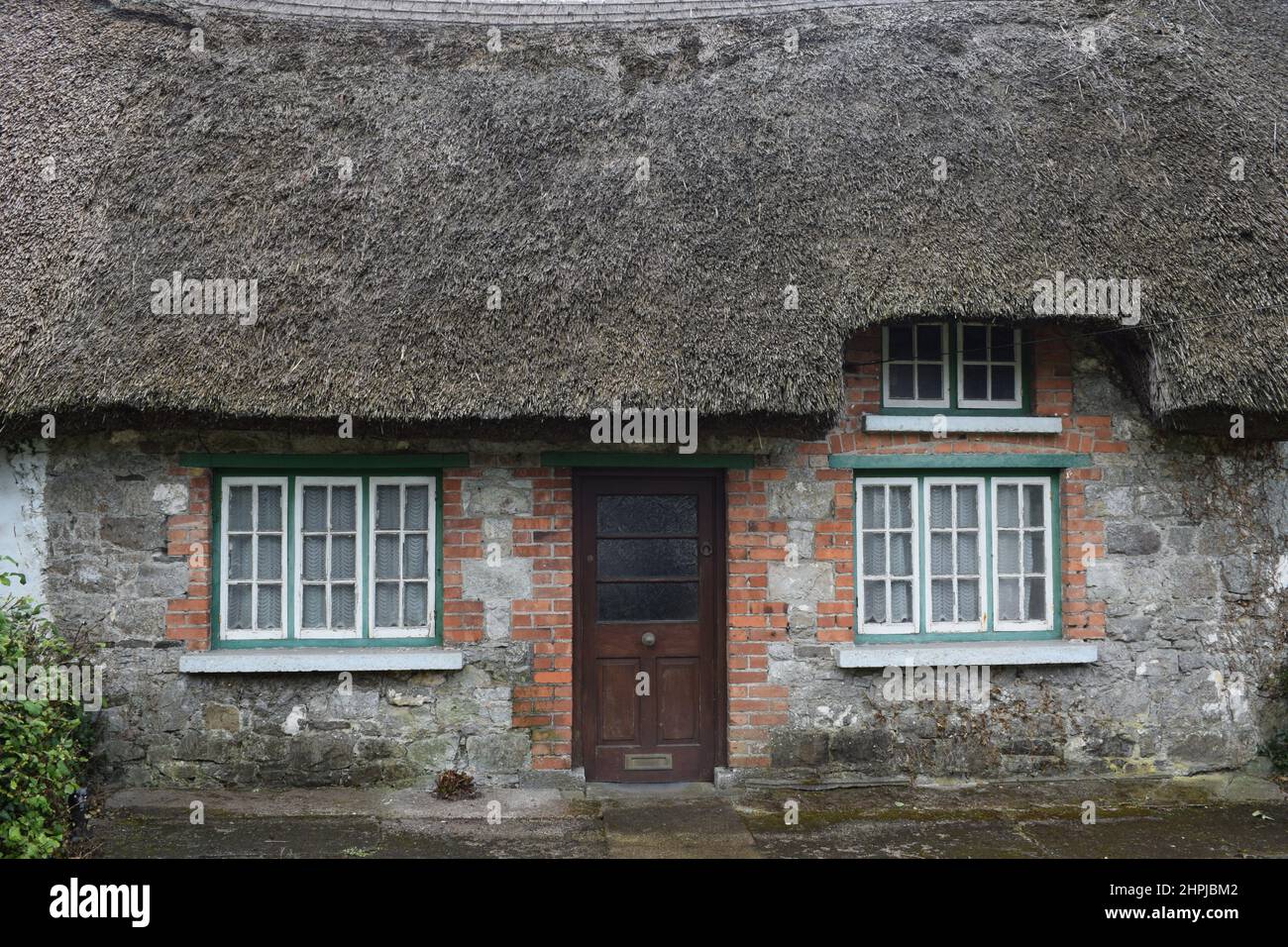 Typical Adare house close up. House close up with thatched roof and brown bricks. Adare Village. Ireland. Stock Photo