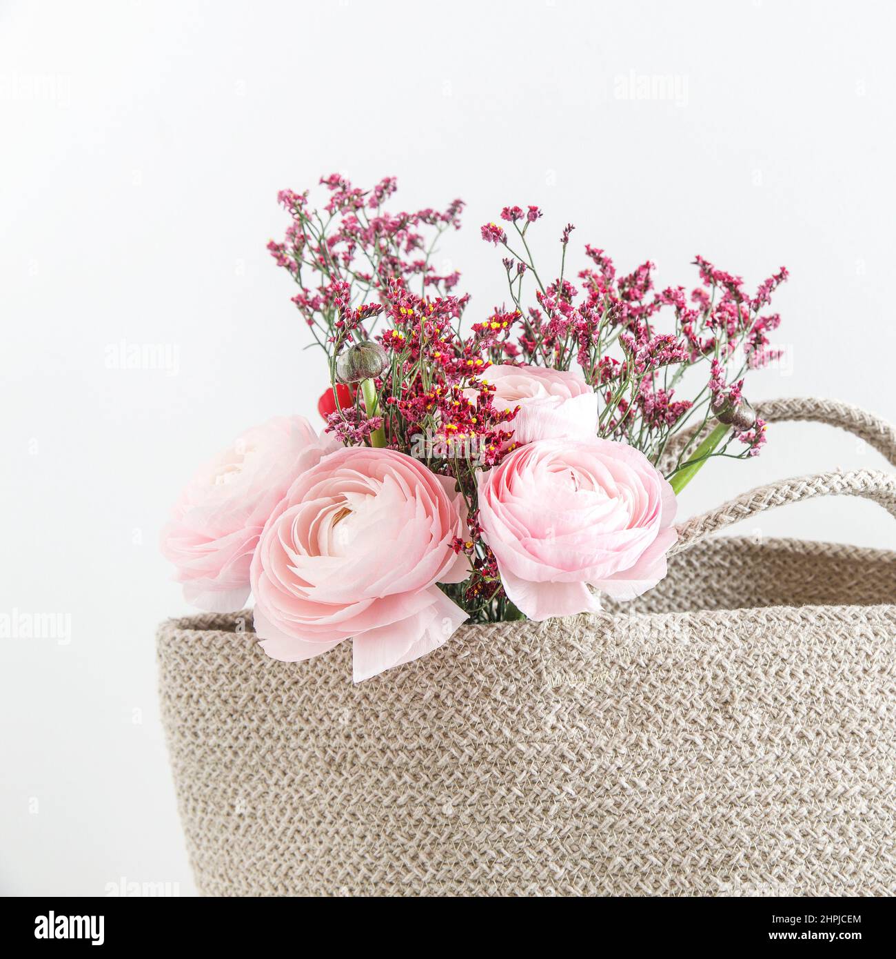 Persian pink buttercup in a beige wicker basket on a white background. Copy space Stock Photo