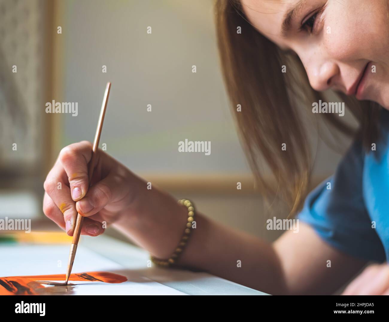 cute girl at home at the table draws with paints Stock Photo
