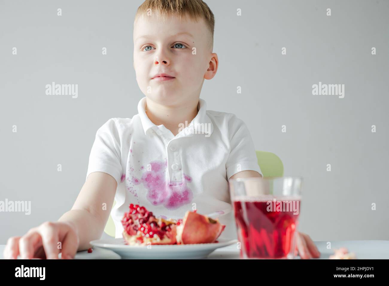 The boy opening a pomegranate and soiling his clothes. daily life dirty