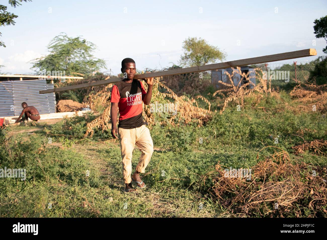 A man is seen carrying a piece of wood for building a pit latrine at ...