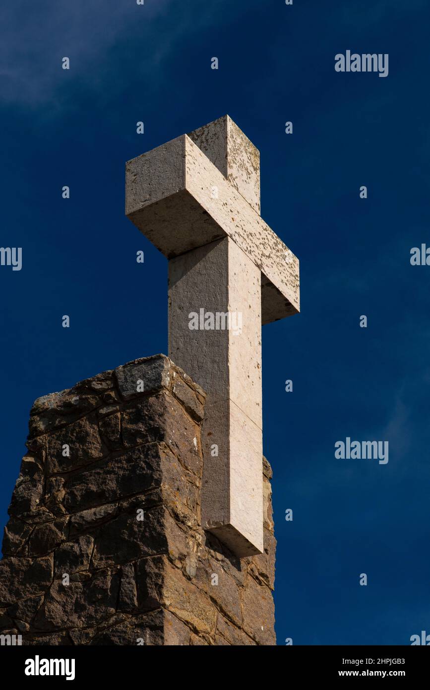 This plain white cross surmounts a stone monument at the place in Portugal 'where the land ends and the sea begins': the wild and windswept Cabo da Roca promontory, renowned as the westernmost point in continental Europe, with its rugged near-vertical granite and limestone cliffs jutting into the Atlantic Ocean about 42 km (26 miles) from Lisbon. Stock Photo