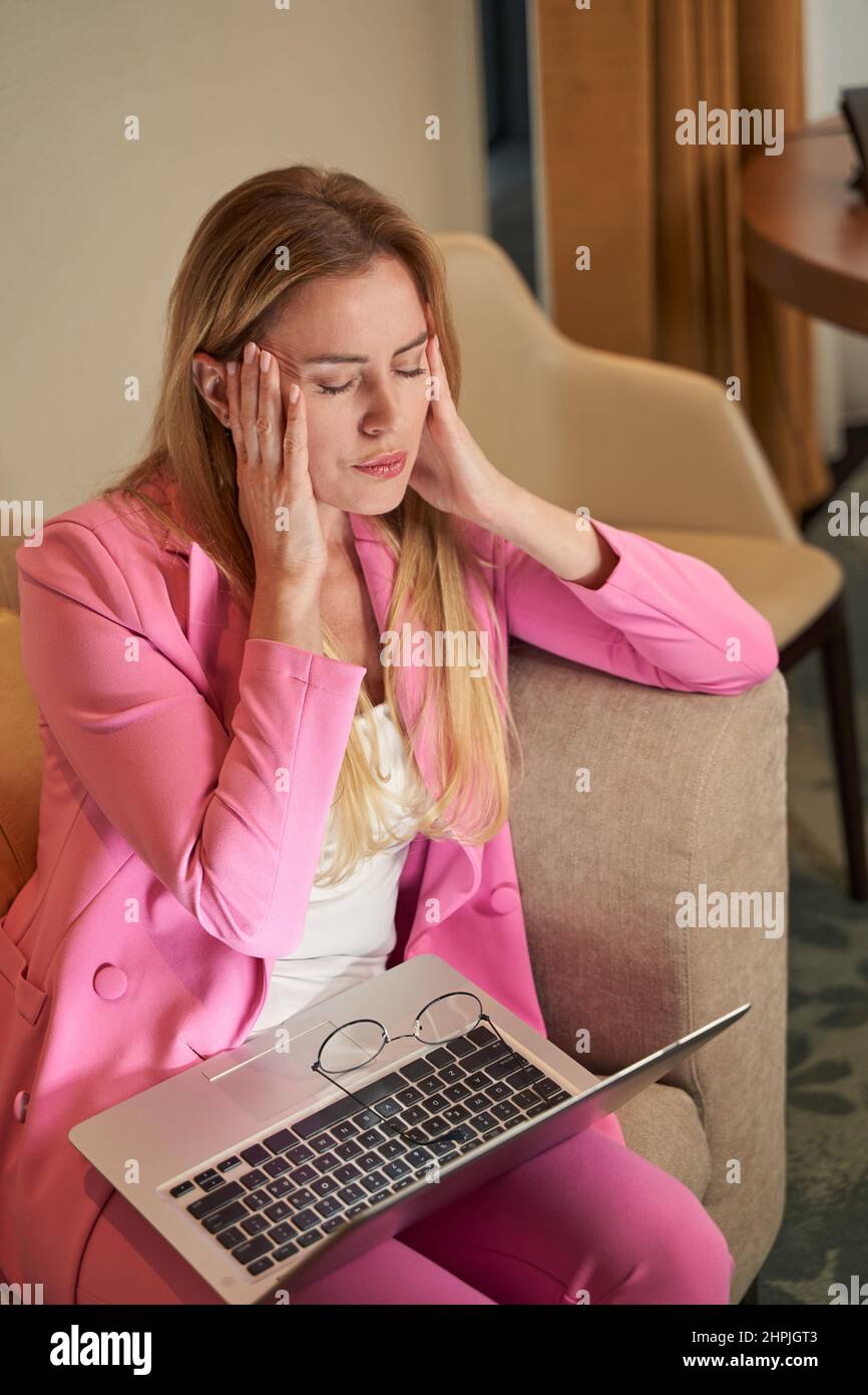 Sad businesswoman suffering from headache at hotel room Stock Photo
