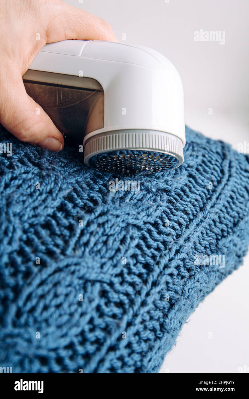 Removing shaving lint fuzz from blue woolen coat sweater, wool clothes