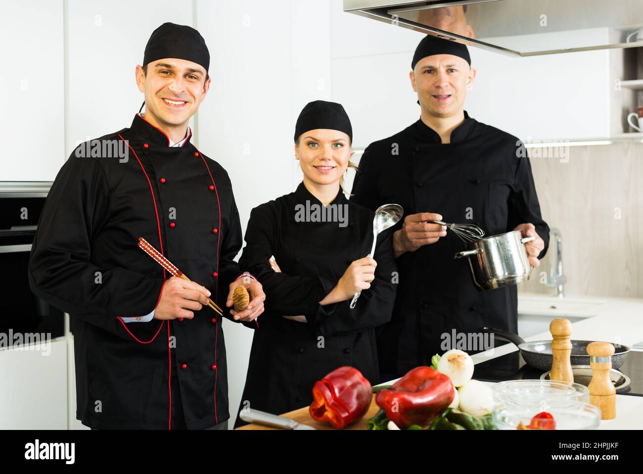 Three young cooks wearing black uniform showing thumbs up Stock Photo ...