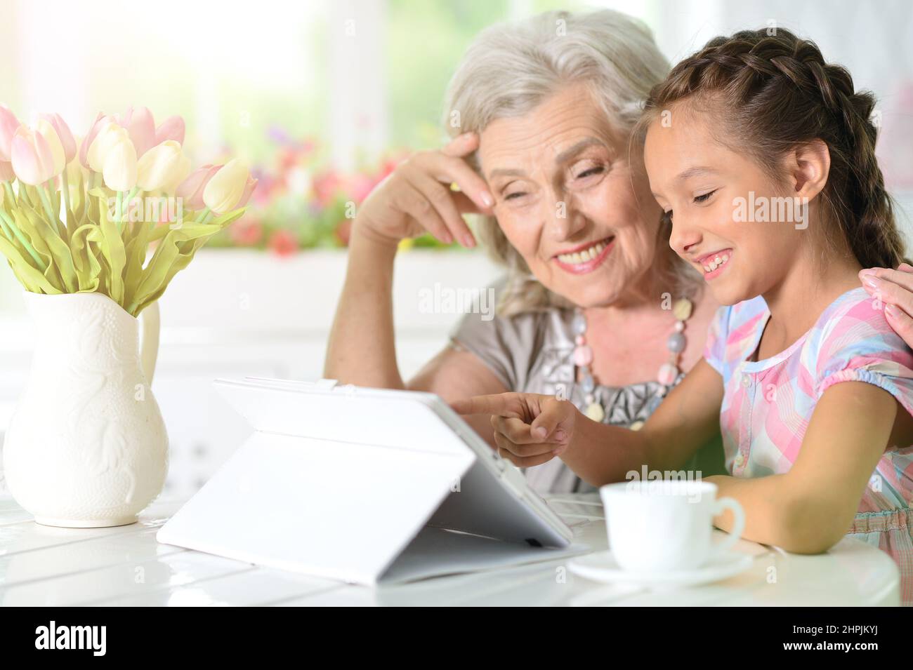 Cute little girl with her grandmother looking at tablet Stock Photo - Alamy