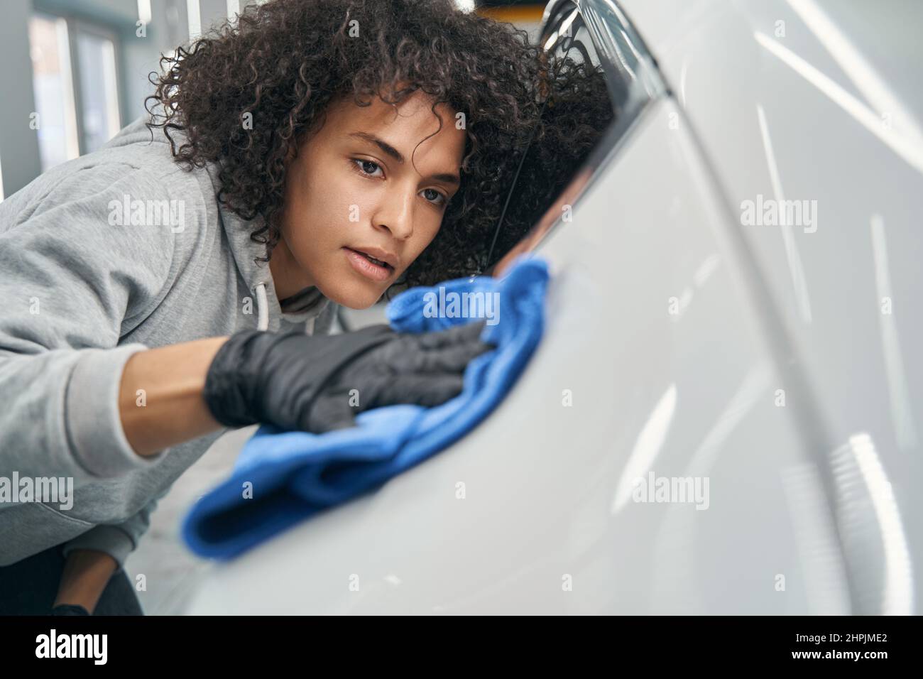 Concentrated young auto detailer buffing motorcar exterior Stock Photo