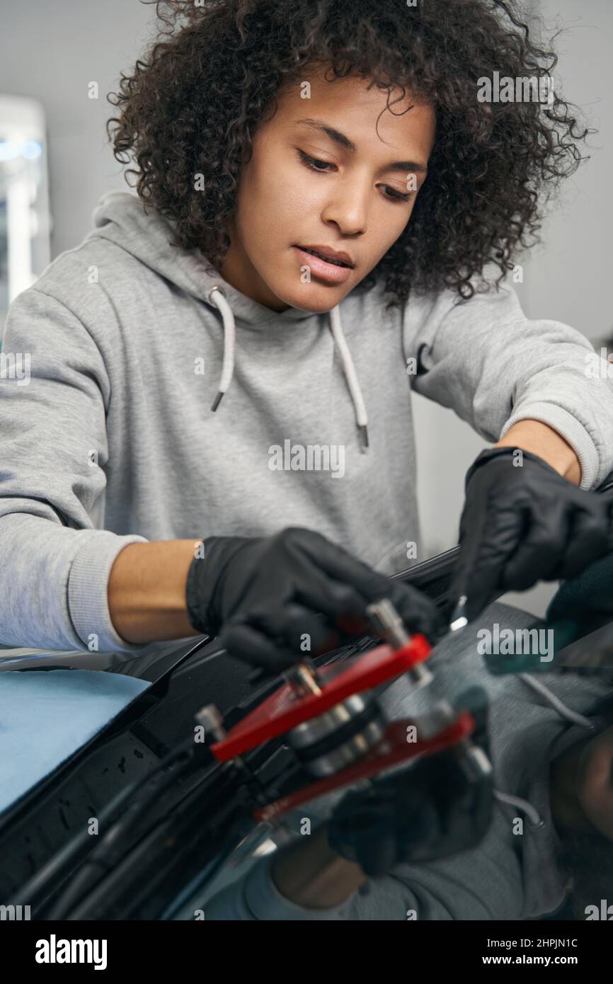 Concentrated auto mechanic installing windshield crack repair bridge