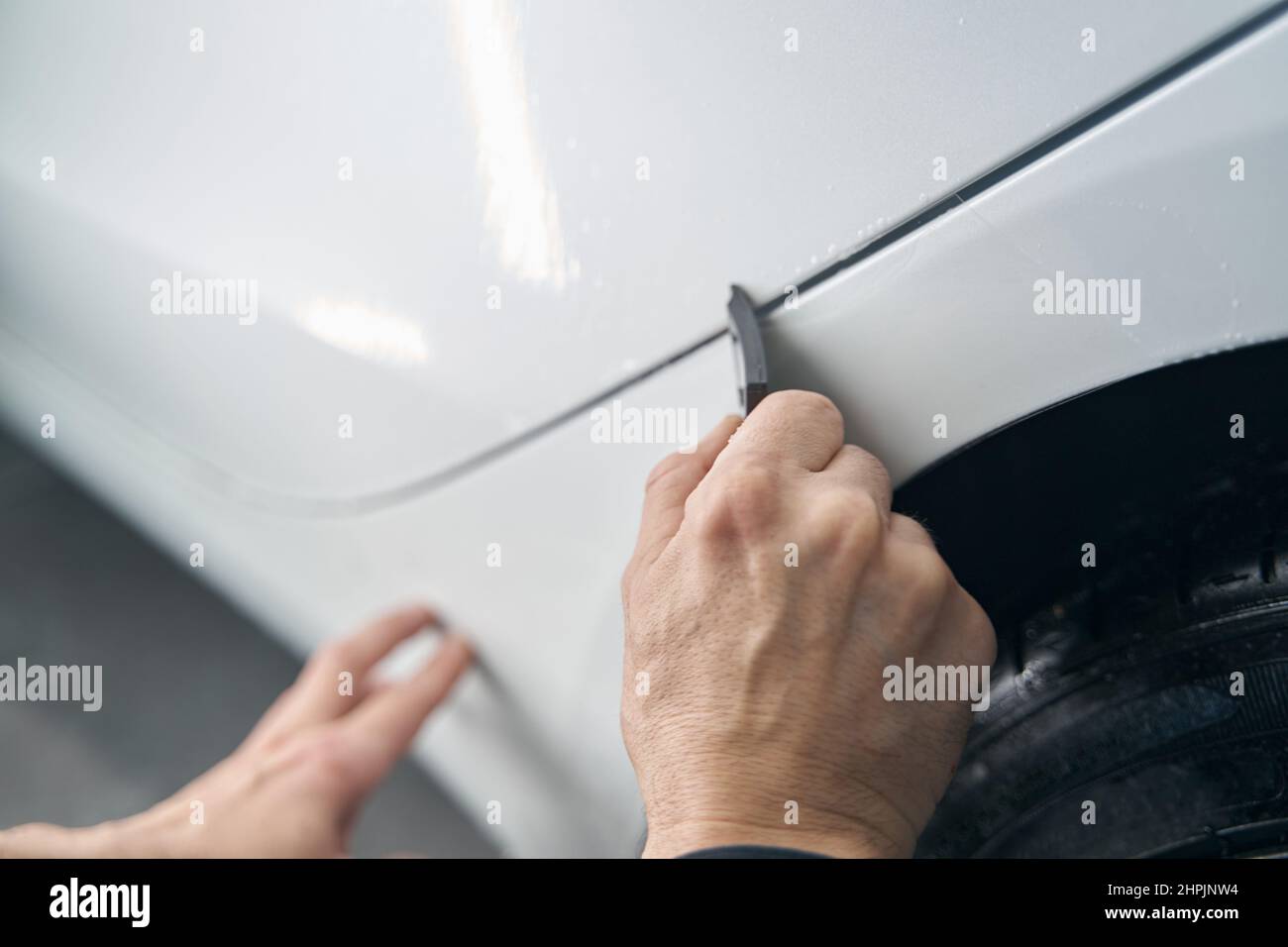 Experienced detailer buffing automotive surface using tool Stock Photo