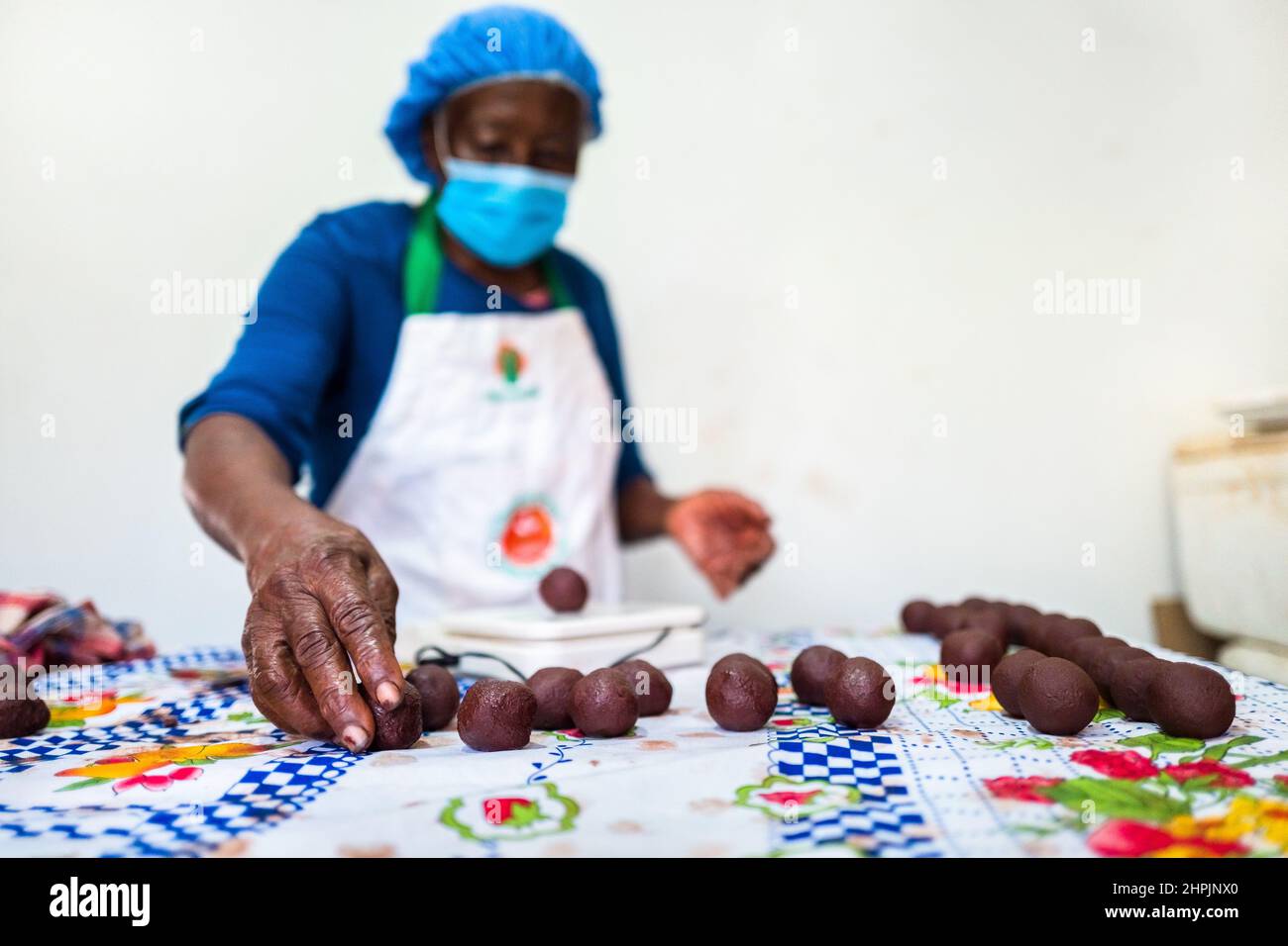 An Afro-Colombian farmer rolls the raw cacao paste with hands into balls in a chocolate manufacture in Cuernavaca, Cauca, Colombia. Stock Photo