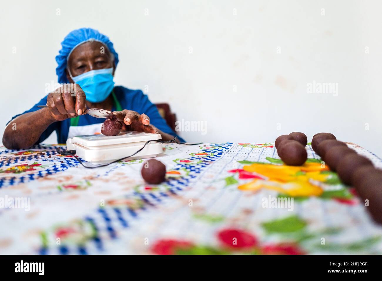 An Afro-Colombian farmer rolls the raw cacao paste with hands into balls in a chocolate manufacture in Cuernavaca, Cauca, Colombia. Stock Photo