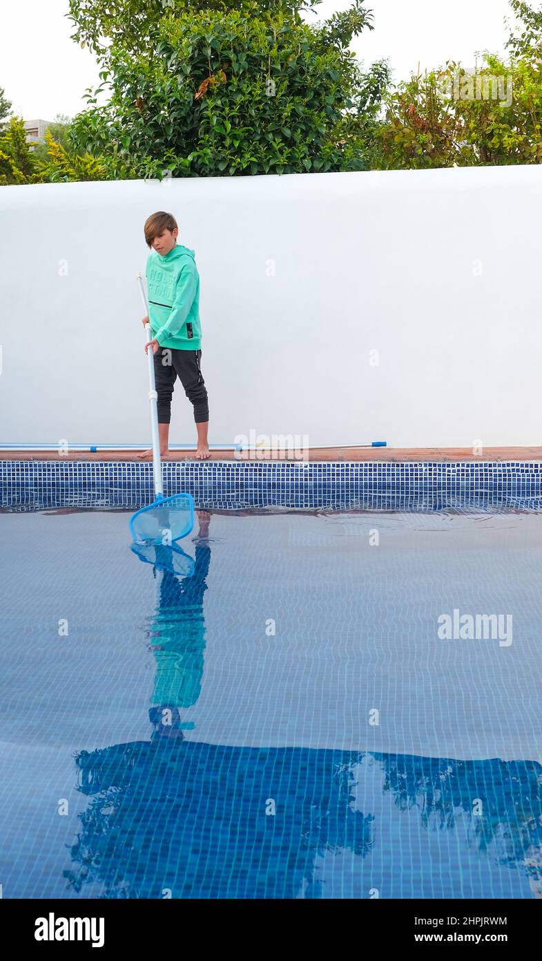 Boy cleaning swimming pool. Teenager after school and house help job