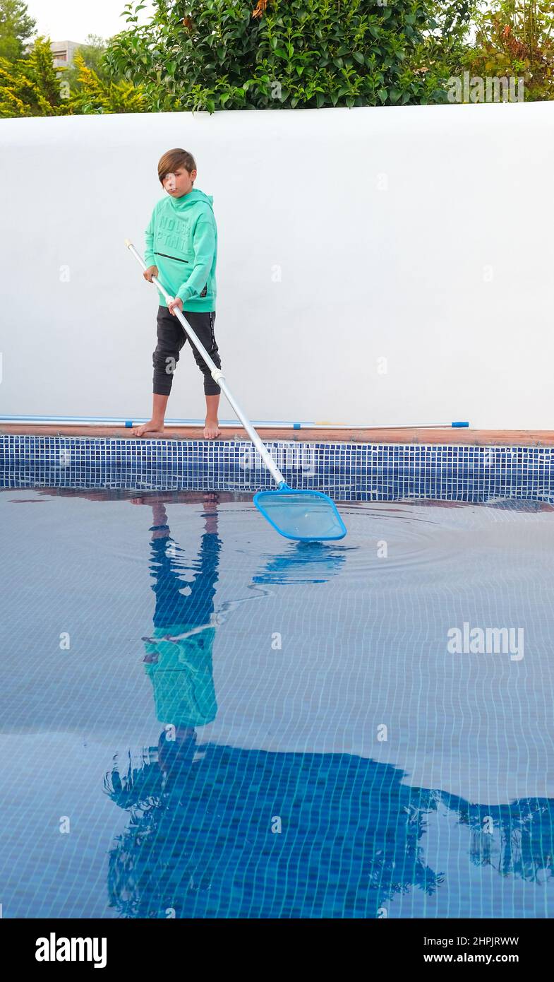 Boy cleaning swimming pool. Teenager after school and house help job