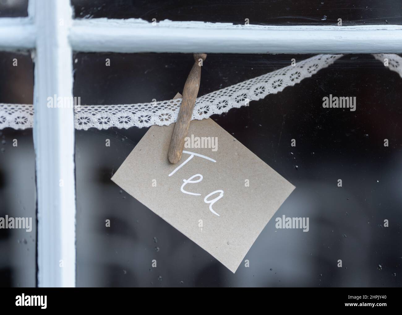 Tea sign pegged to lace in shop window advertising hot drinks to customers of takeaway cafe Stock Photo