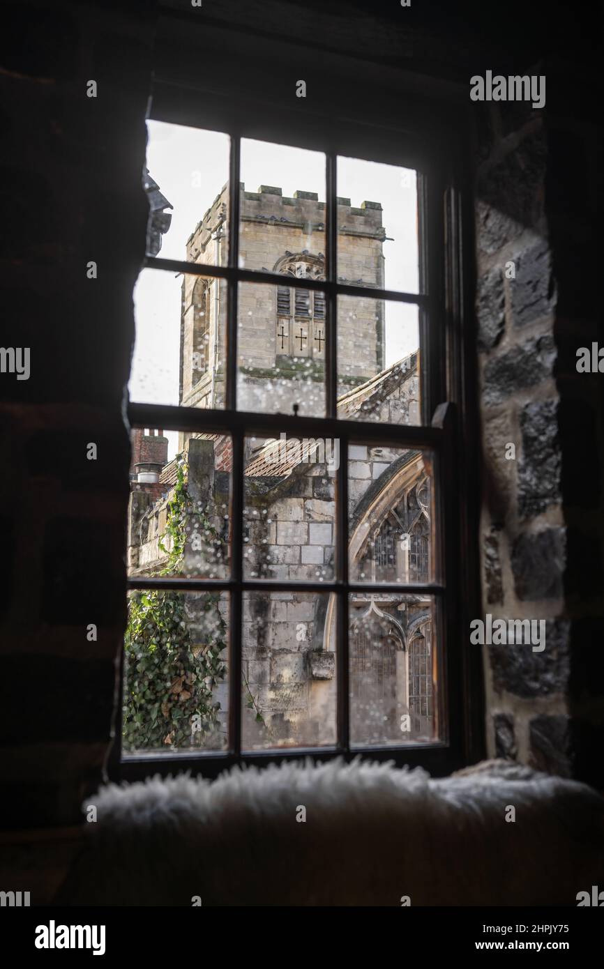 Old medieval churched viewed through pane glass window on rainy day in ancient English city. Stock Photo