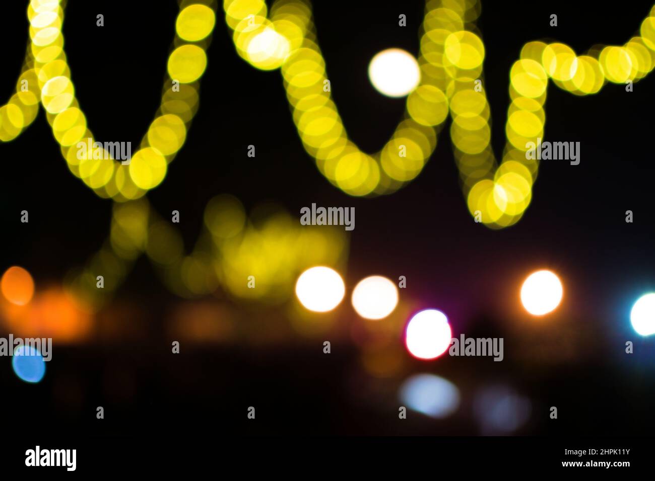 Bokeh light of yellow color in curved shapes with black background during special occasion of festival. Stock Photo