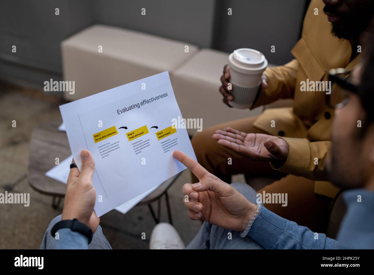 Hand of young confident businessman pointing at business document while analyzing data and explaining it to African-American colleague Stock Photo