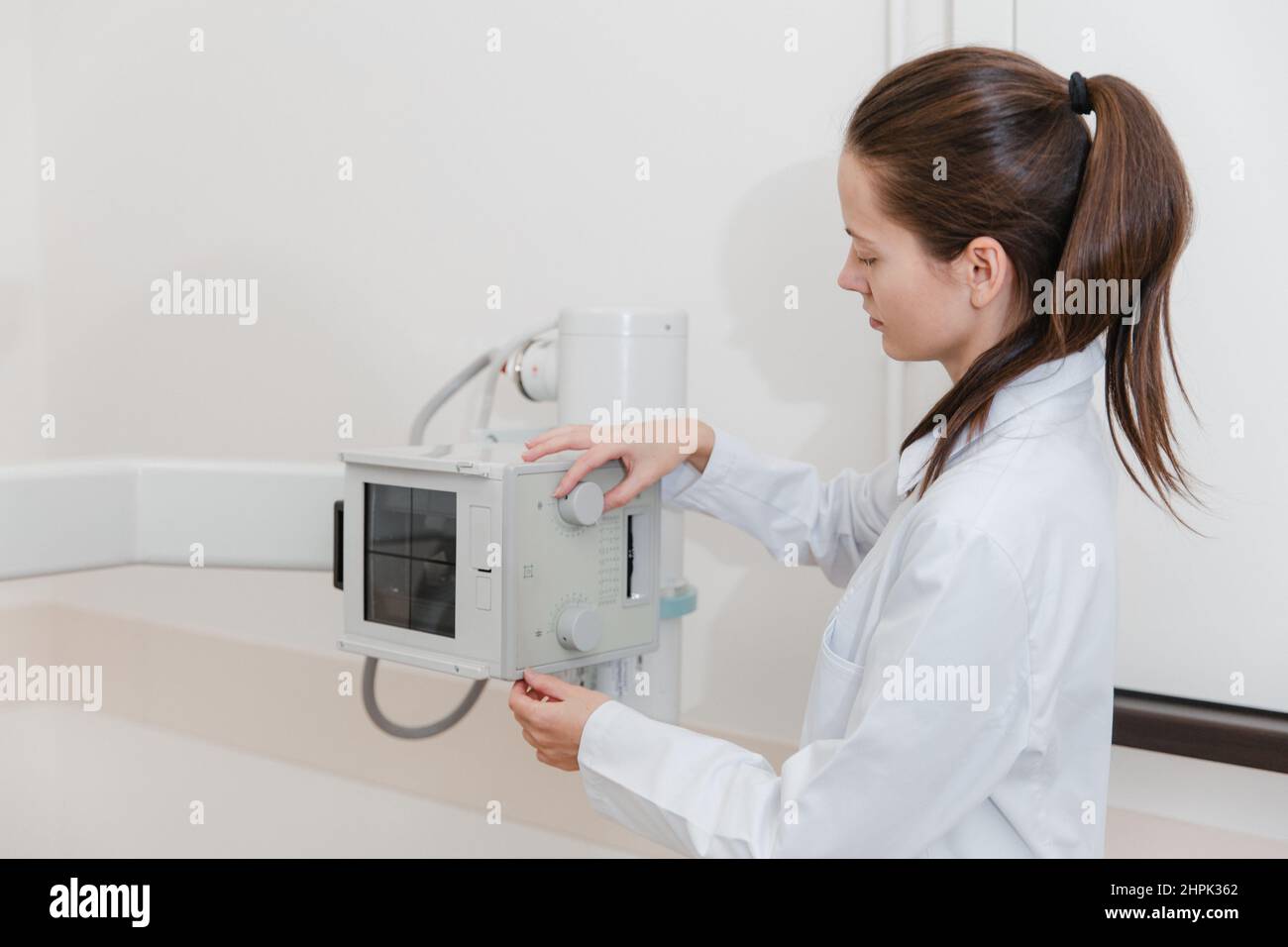 Hospital Radiology Room. Xray machine for fluorography. Doctor radiologist in gown adjusting the