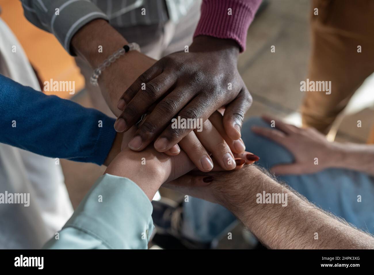 Pile of hands of multi-ethnic group of contemporary employees symbolizing partnership, business union, team building and company spirit Stock Photo