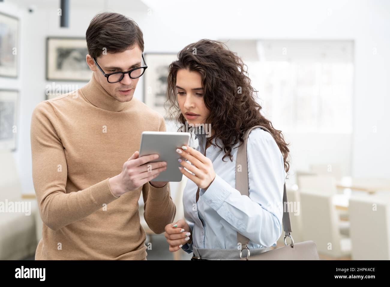 Young confident programmer of high tech company making presentation of online data analysis to colleague or client in large modern office Stock Photo