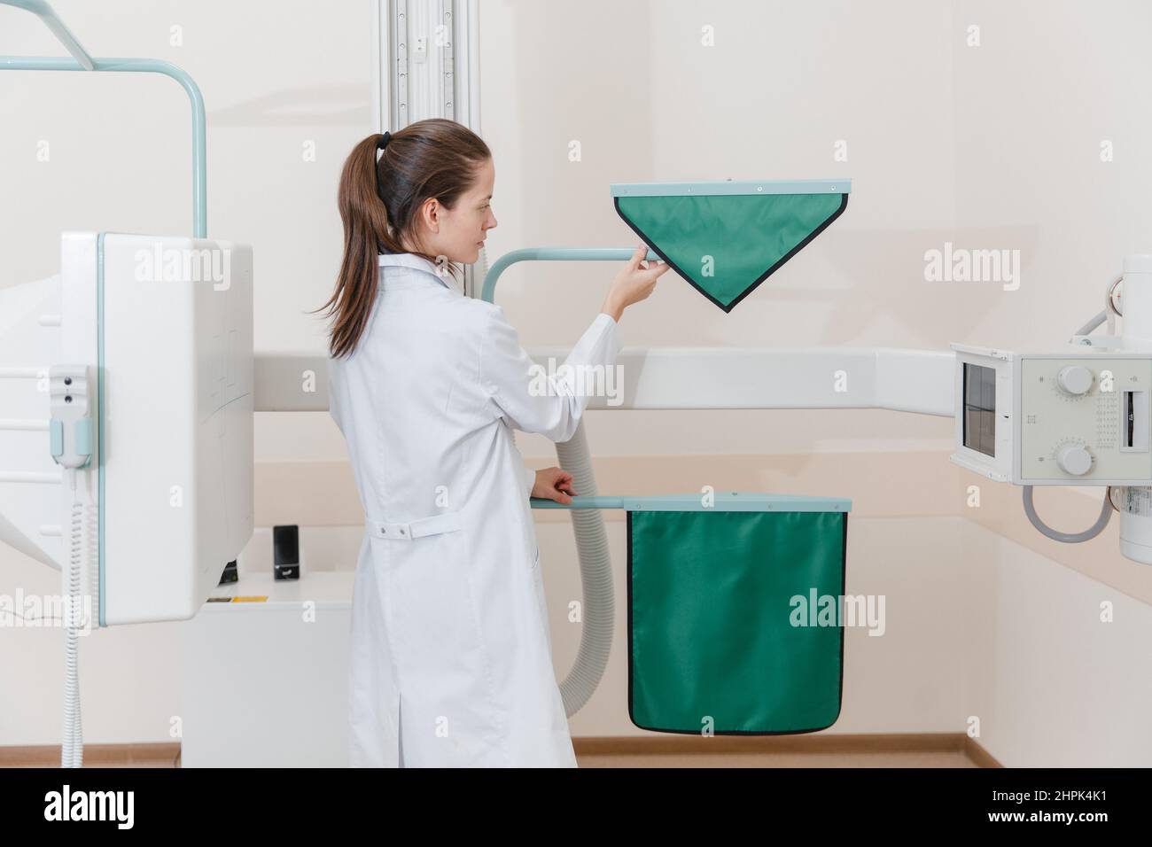 Hospital Radiology Room. Xray machine for fluorography. Doctor radiologist in gown adjusting the X-ray machine for radiography. Medical equipment Stock Photo