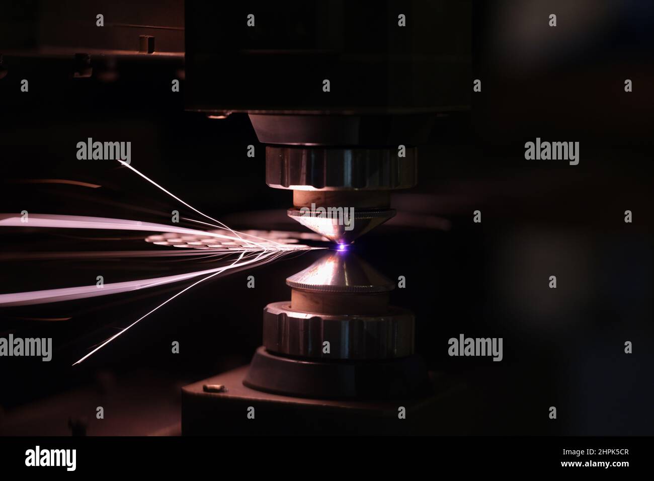 Laser machine cutting sheet of metal with bright sparks closeup Stock Photo