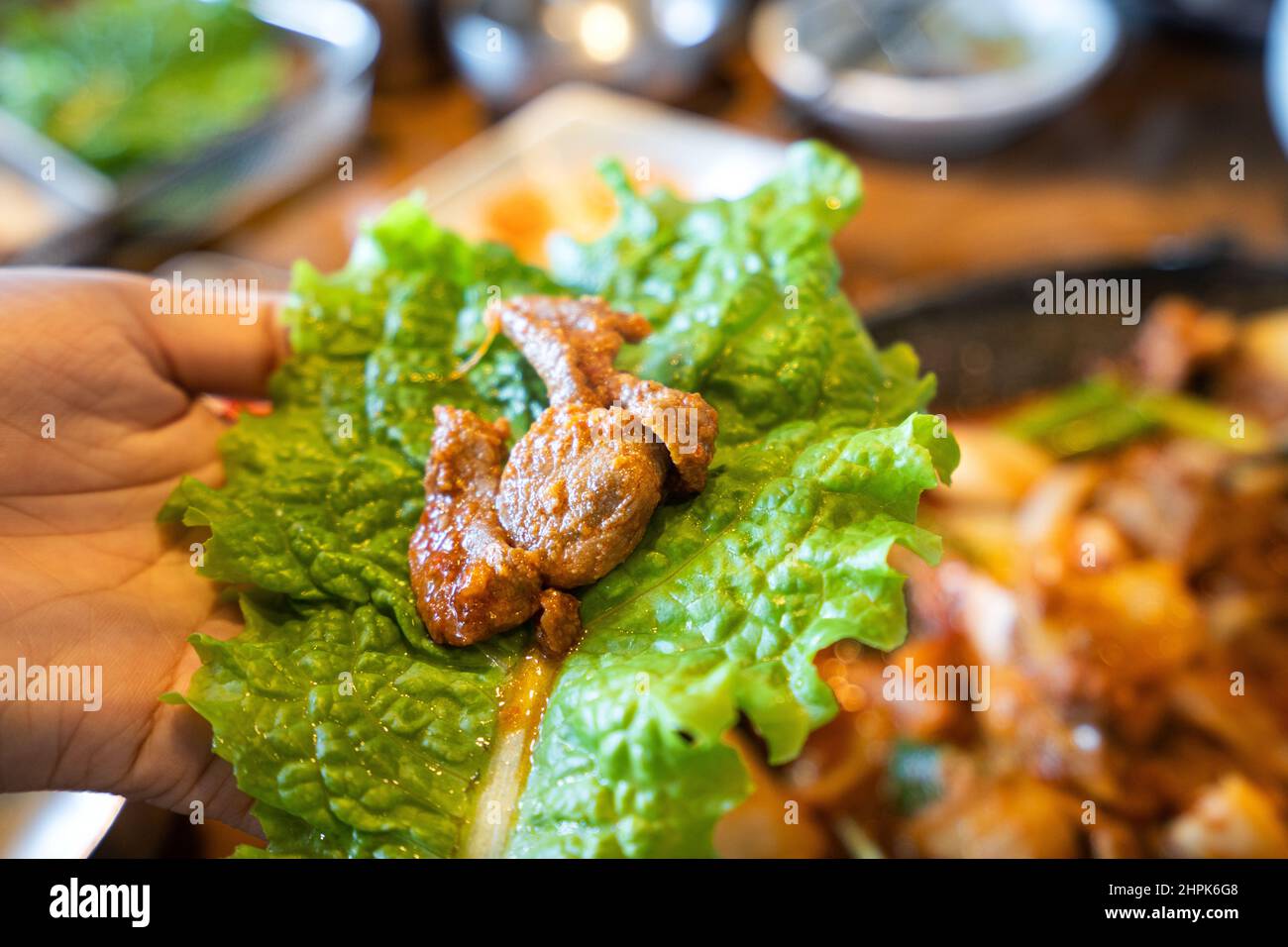 Close up of ssam Korean BBQ, pan-fried black pork with lettuce meal in ...