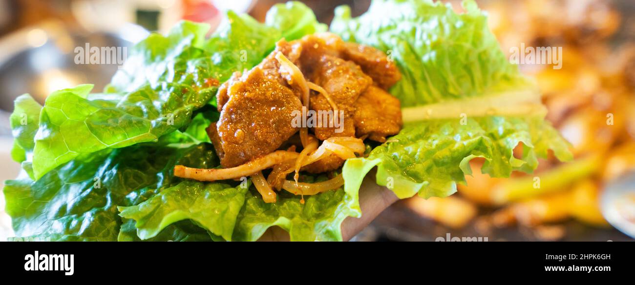 Close up of ssam Korean BBQ, pan-fried black pork with lettuce meal in Korea restaurant, fresh delicious korean cuisine. Stock Photo