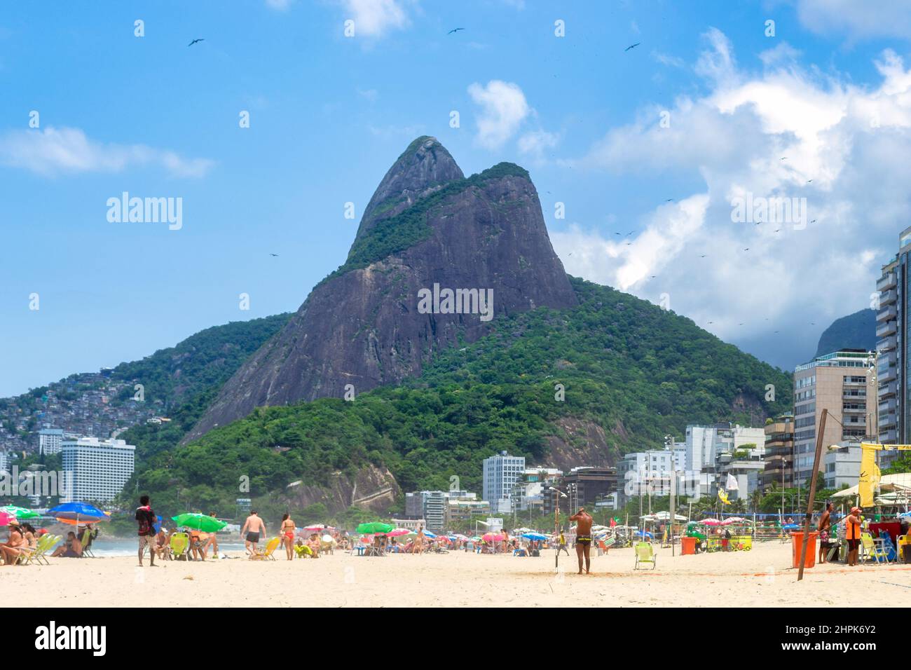 The Two Brothers Mountain seen from the sand where tourists are enjoying the Summer. Ipanema Beach is a famous place and a major travel destination in Stock Photo