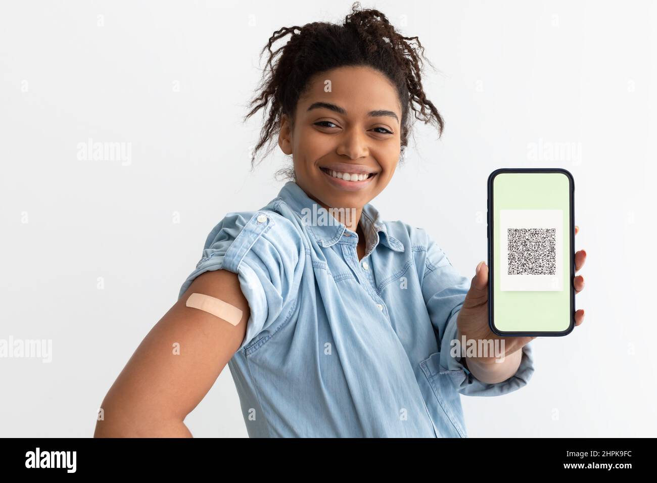 Black lady showing adhesive plaster on arm and digital certificate Stock Photo
