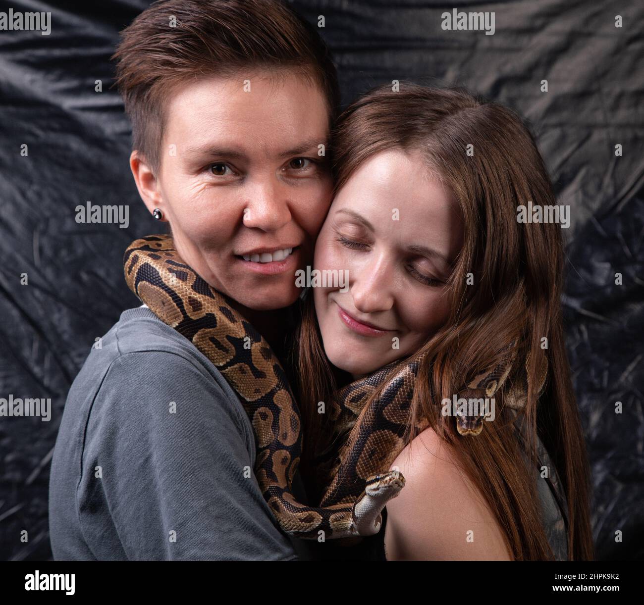 Photo of two happy women with python on neck Stock Photo
