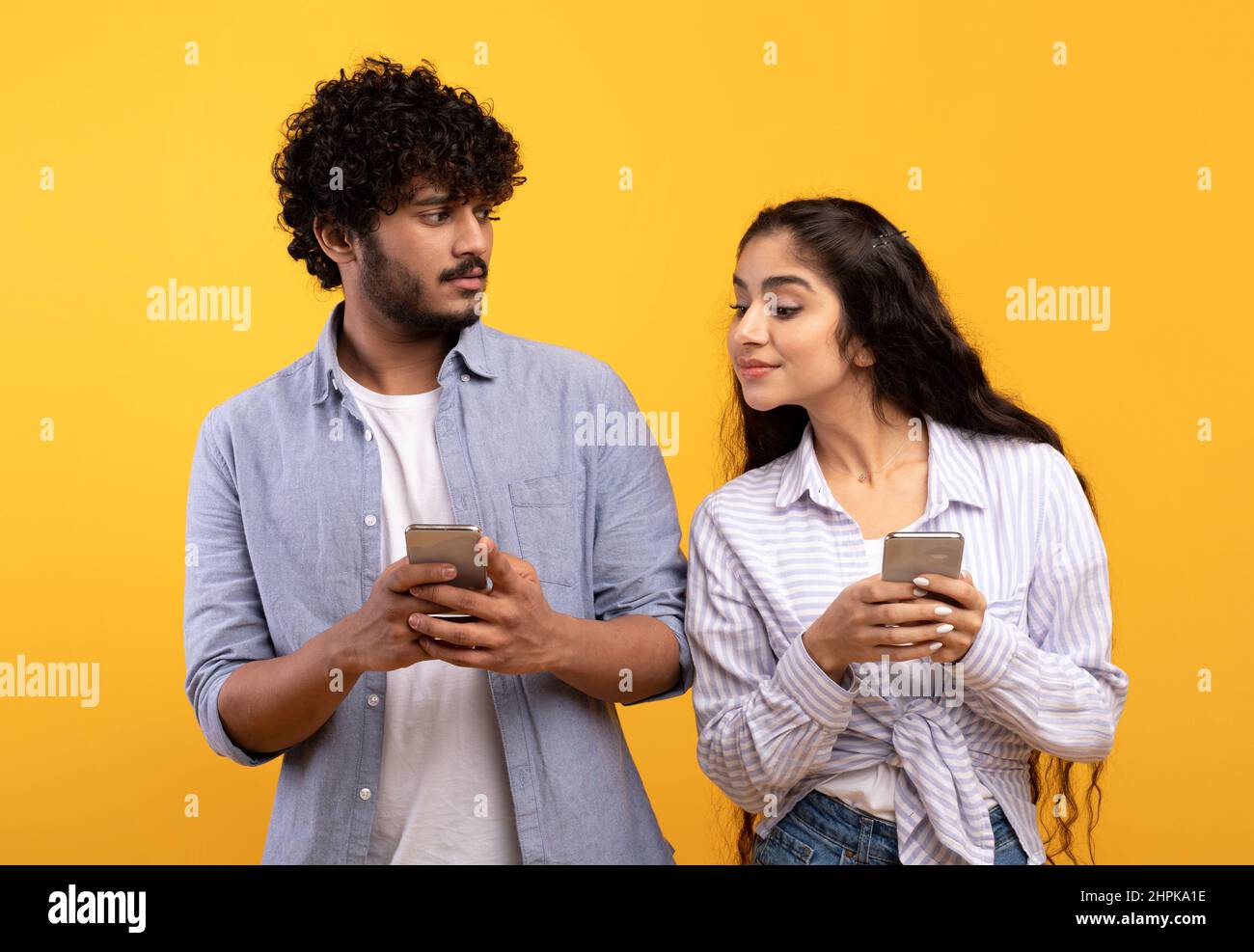 Shocked indian woman spying on her boyfriend using smartphone, texting sms or scrolling social media news feed Stock Photo