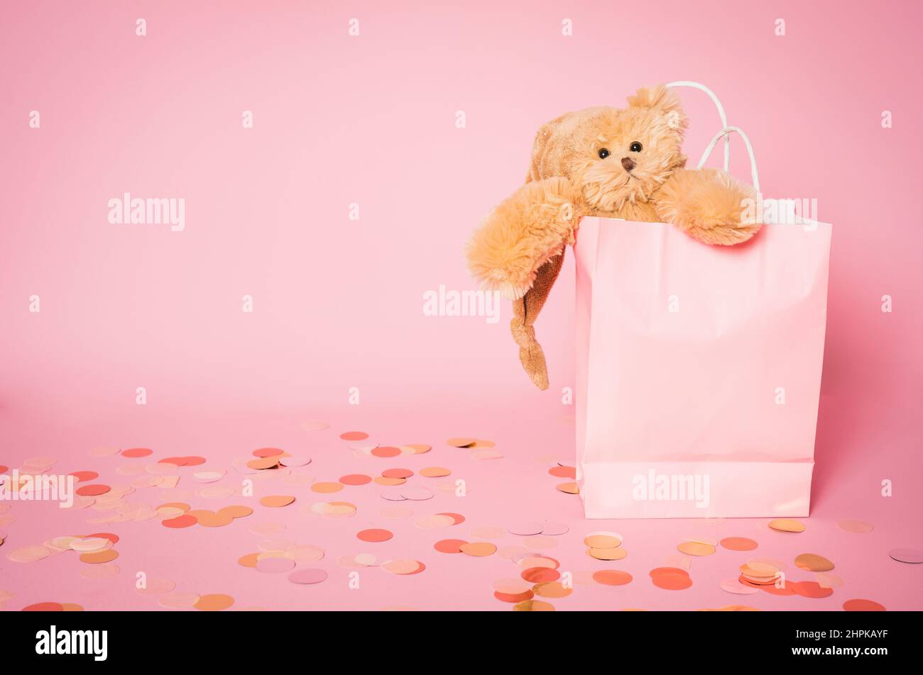 Teddy bear in pink paper bag isolated over pink background. Stock Photo
