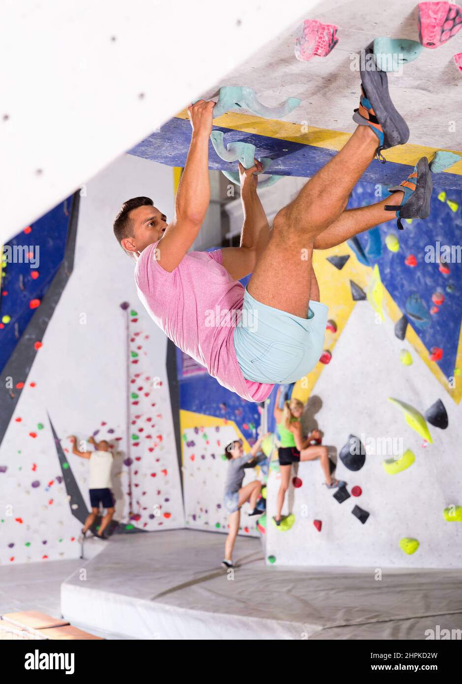 Male alpinist practicing indoor rockclimbing on artificial boulder