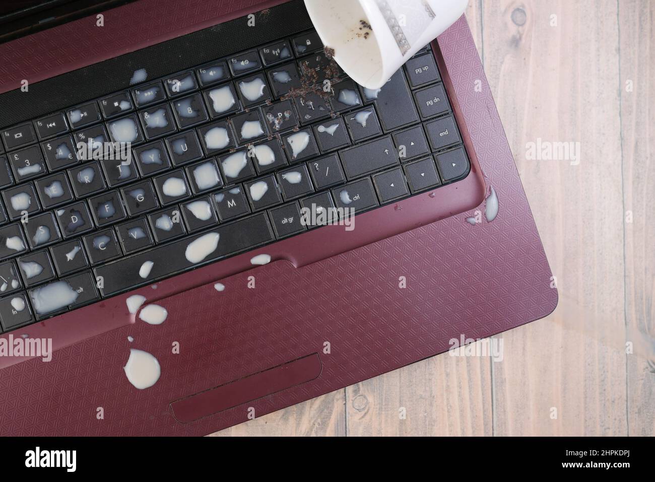 tea spilling over a laptop keyboard on table  Stock Photo