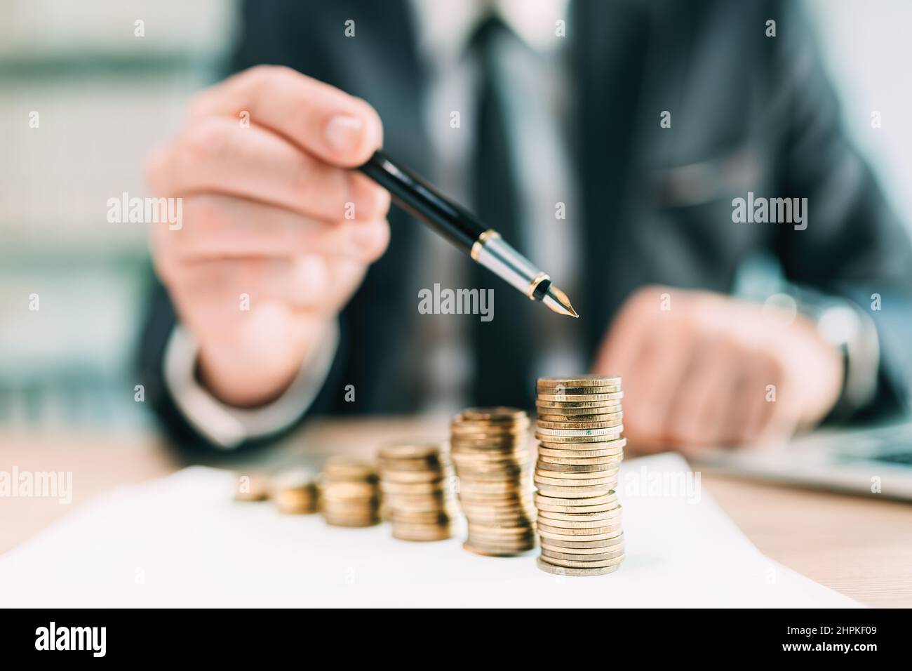 Investment return concept, businessman pointing to a coin stack at office desk, selective focus Stock Photo